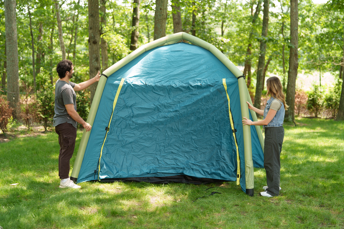 couple setting up a blue and green tent on top of grass