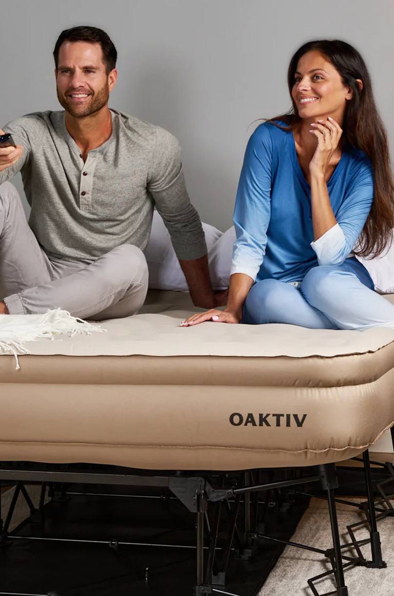 Man and woman sitting on an inflatable bed with 'Oaktiv' branding.