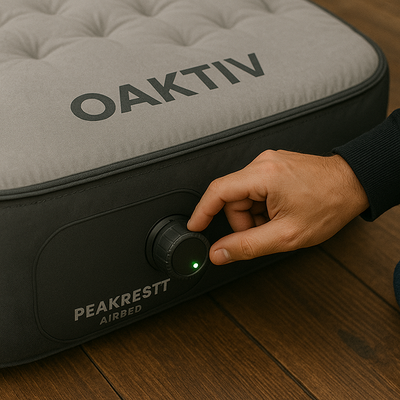 Hand adjusting a knob on a Peakrestt airbed with 'Oaktiv' branding.