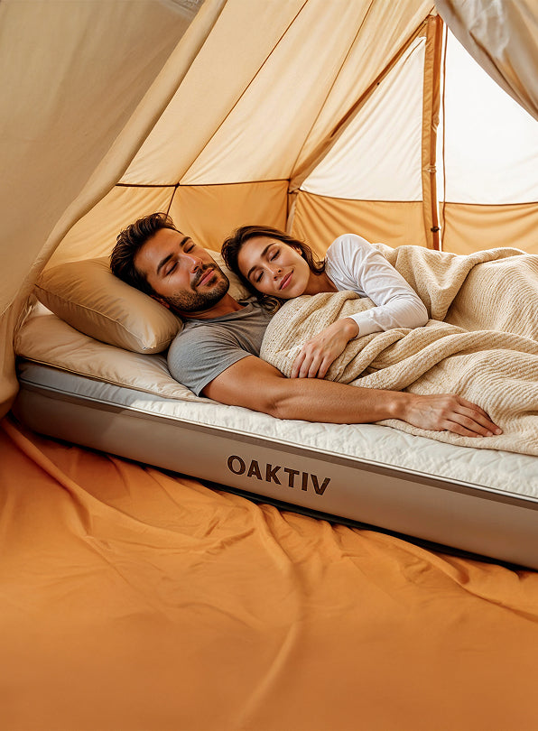 Couple lying on a camping mattress with 'OAKTIV' branding inside a tent.